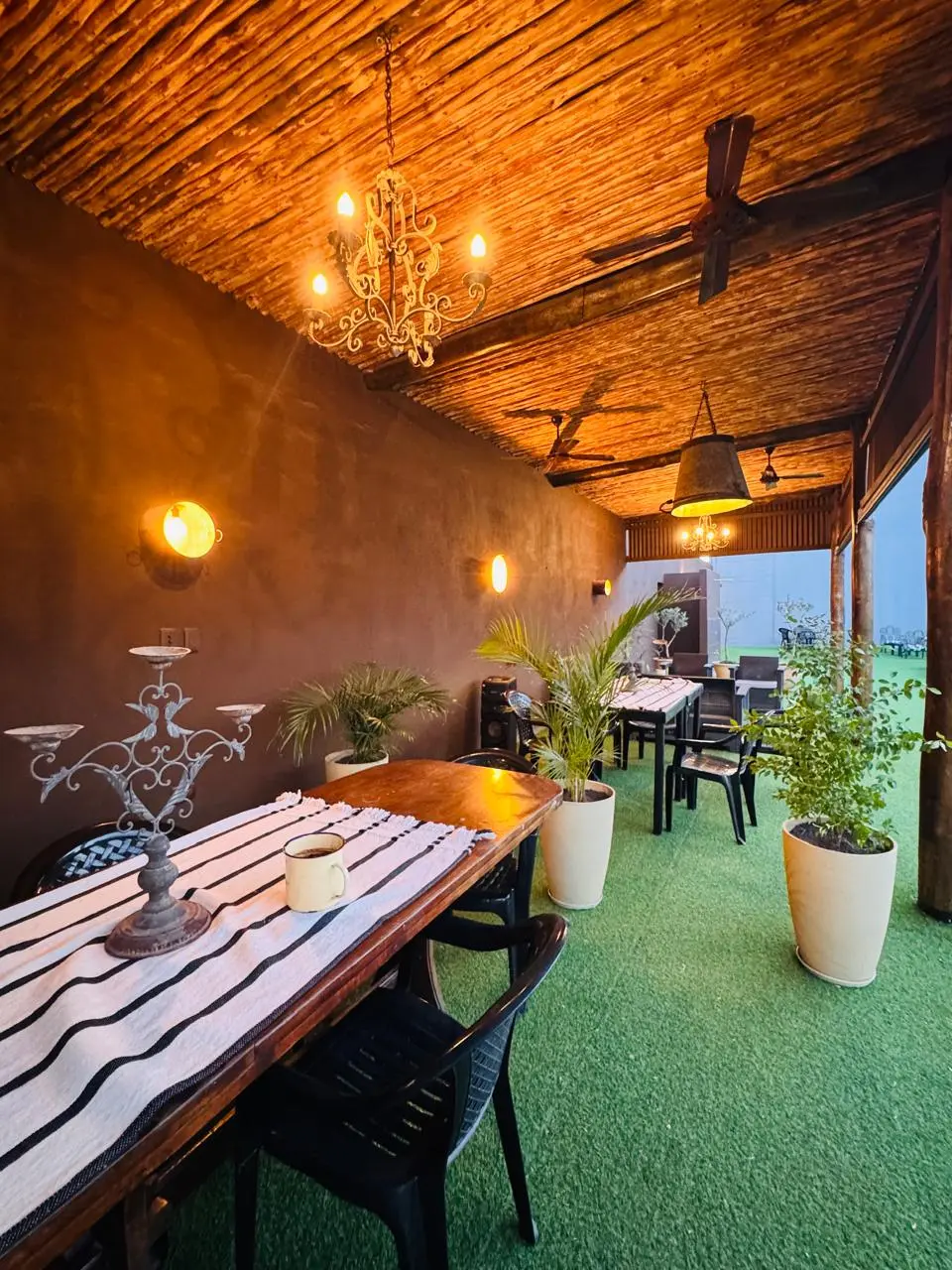 Sala de bar techada con mesas largas y arañas de luz